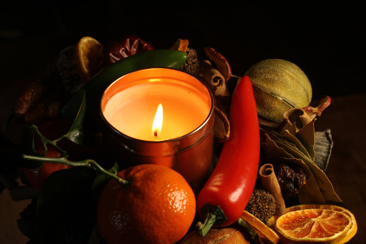Irish Soy Wax Candle in a copper tin surrounded by fruits, chilli and herbs on a dark background