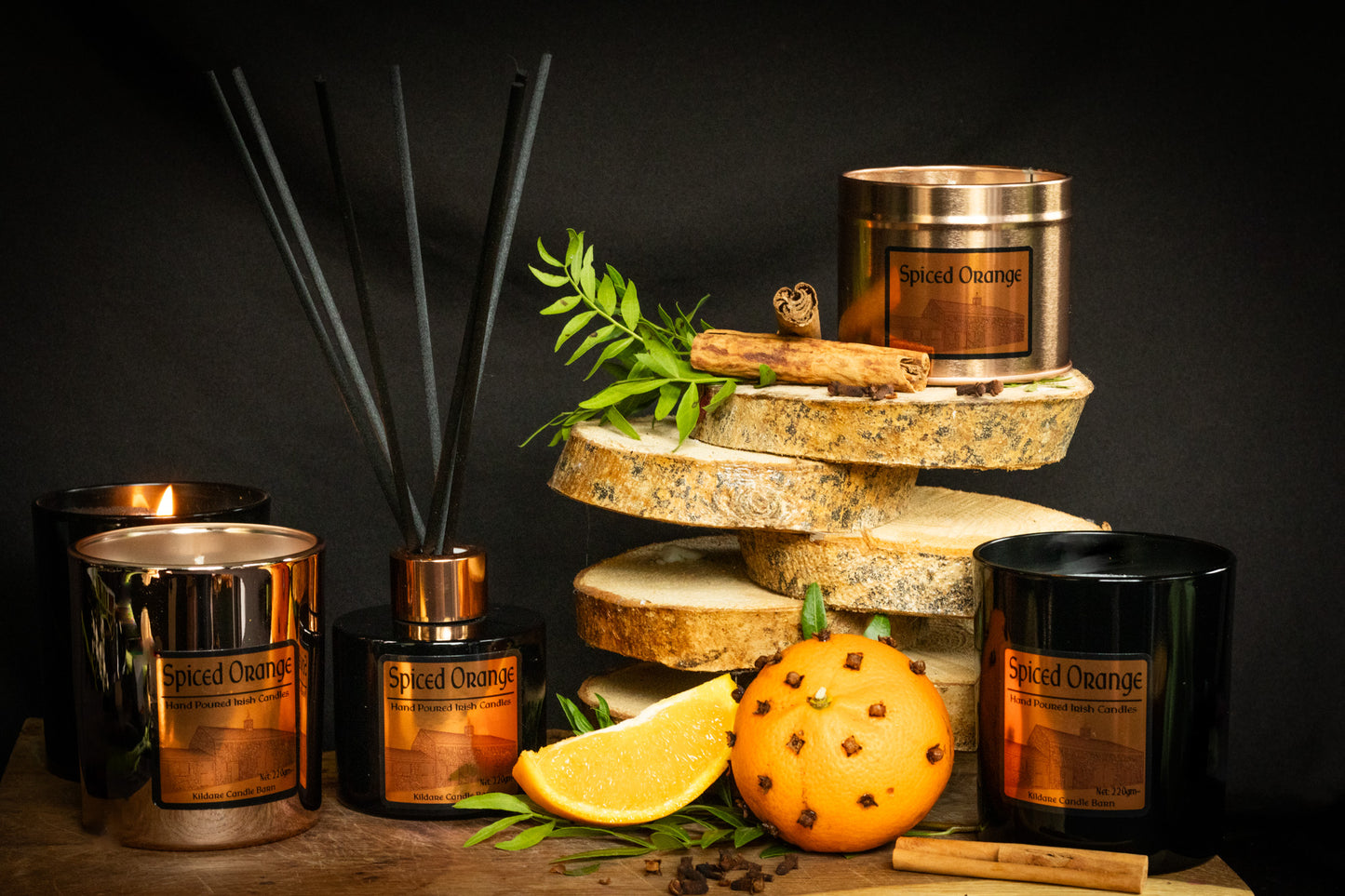 Spiced Orange fragrance products including natural candles and diffusers on a dark background