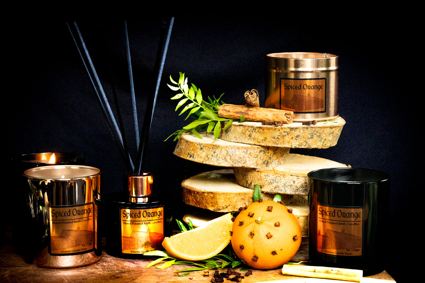 Irish Soy Wax Candles, a diffuser, and clove studded oranges, lemons , cloves and cinnamons on a dark background