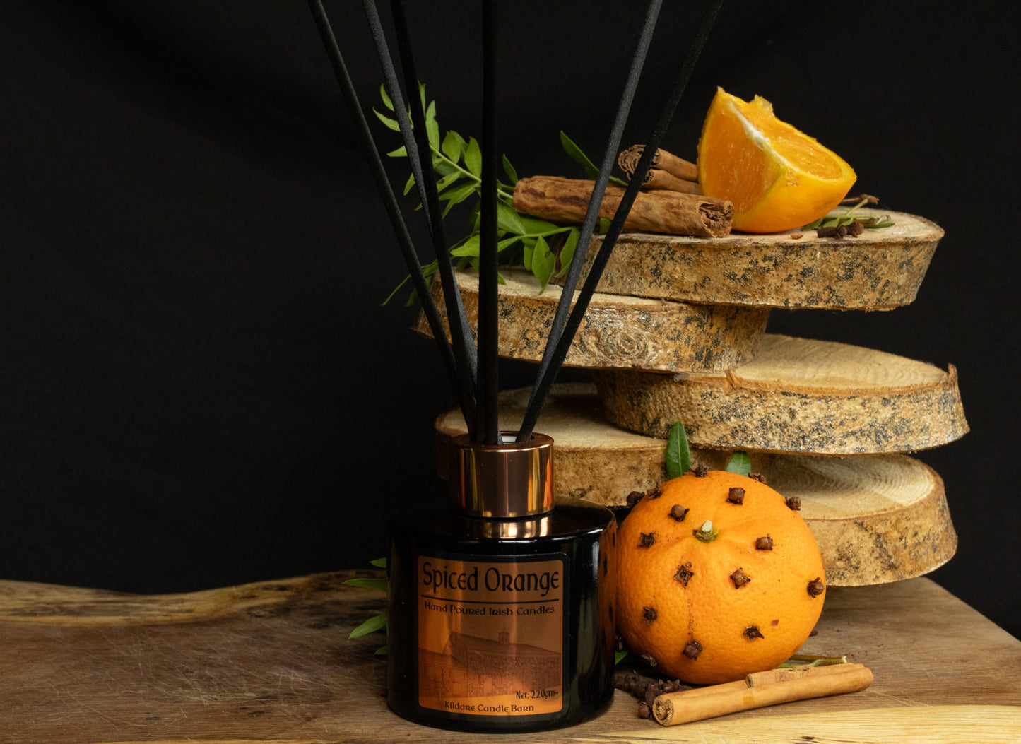 Scented reed diffuser labeled 'Spiced Orange' with decorative elements on a wooden surface.